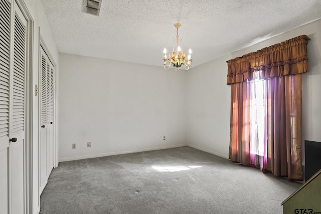 unfurnished bedroom with carpet flooring, a textured ceiling, and an inviting chandelier