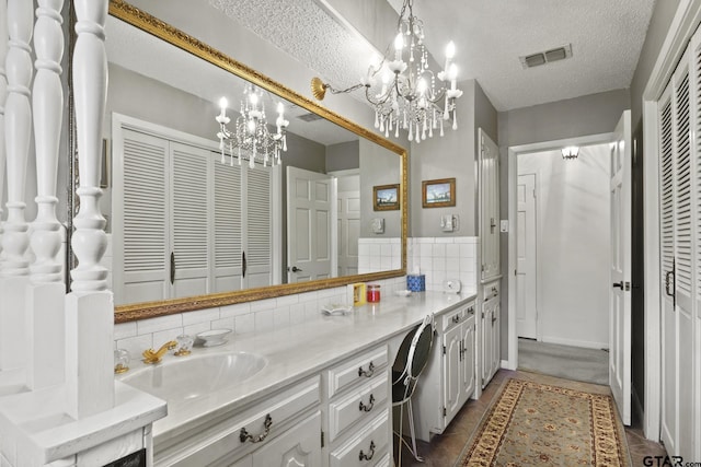 bathroom with vanity, a textured ceiling, and a chandelier