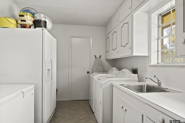 laundry room with sink, cabinets, washing machine and dryer, a textured ceiling, and light tile patterned floors