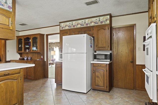 kitchen featuring a textured ceiling, wooden walls, white appliances, and ornamental molding