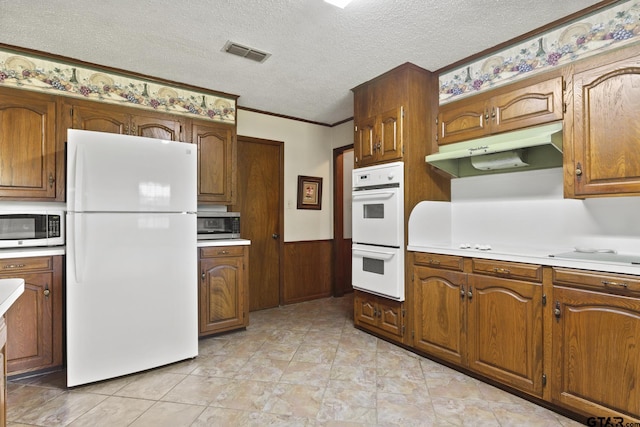 kitchen with a textured ceiling, white appliances, and ornamental molding