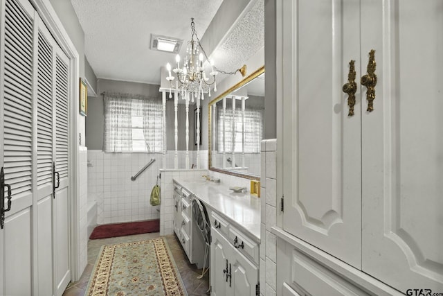 bathroom featuring vanity, tile patterned flooring, a textured ceiling, tile walls, and a notable chandelier