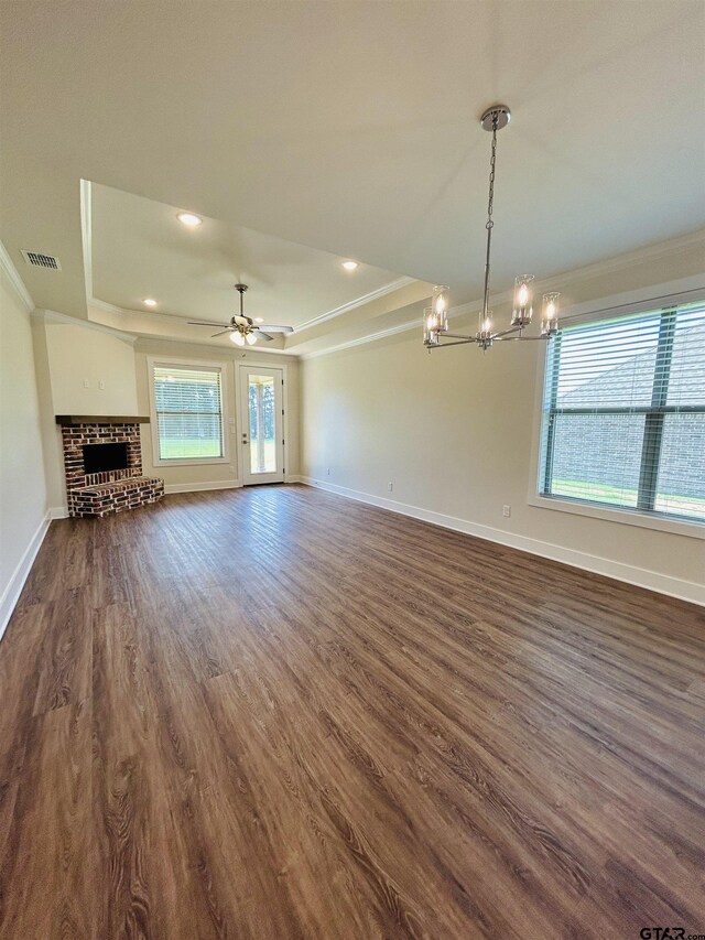 15033 High Country Acres Ln, Tyler, TX 75706 - unfurnished living room with crown molding, a chandelier, a tray ceiling, dark wood-type flooring, and a brick fireplace