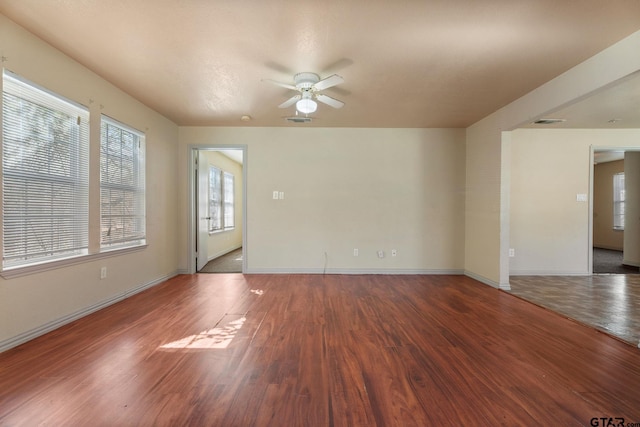 unfurnished room featuring visible vents, ceiling fan, baseboards, and wood finished floors