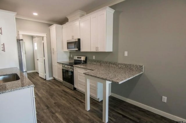 kitchen featuring light stone countertops, appliances with stainless steel finishes, a kitchen breakfast bar, white cabinets, and dark hardwood / wood-style floors