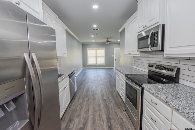 kitchen with appliances with stainless steel finishes, light stone counters, ceiling fan, white cabinets, and dark hardwood / wood-style floors