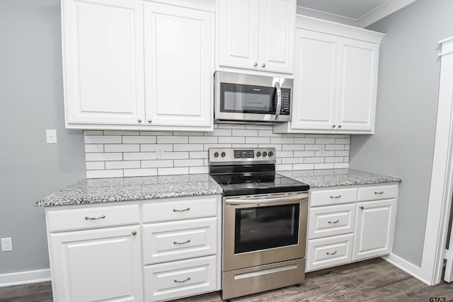 kitchen with white cabinets, stainless steel appliances, light stone counters, and dark hardwood / wood-style floors