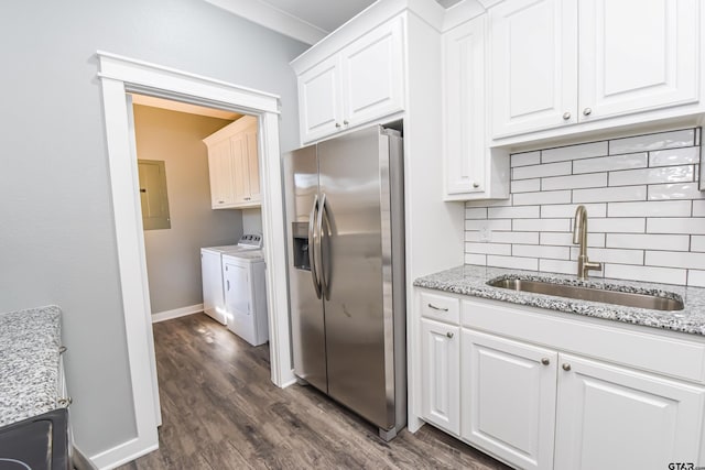 kitchen featuring washer and clothes dryer, stainless steel fridge with ice dispenser, sink, and white cabinets