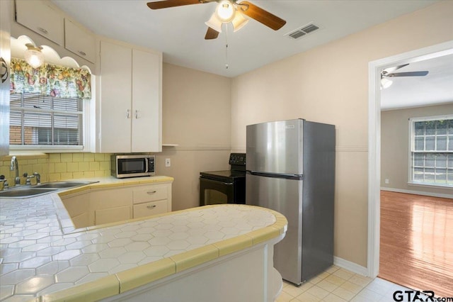 1931 S Wiley, Tyler, TX 75701 - kitchen with stainless steel appliances, tile counters, a ceiling fan, backsplash, and a peninsula