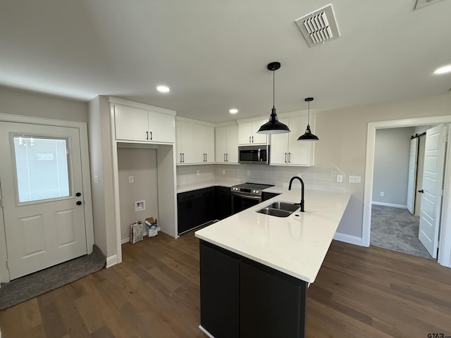 kitchen featuring sink, hanging light fixtures, a barn door, white cabinetry, and stainless steel appliances