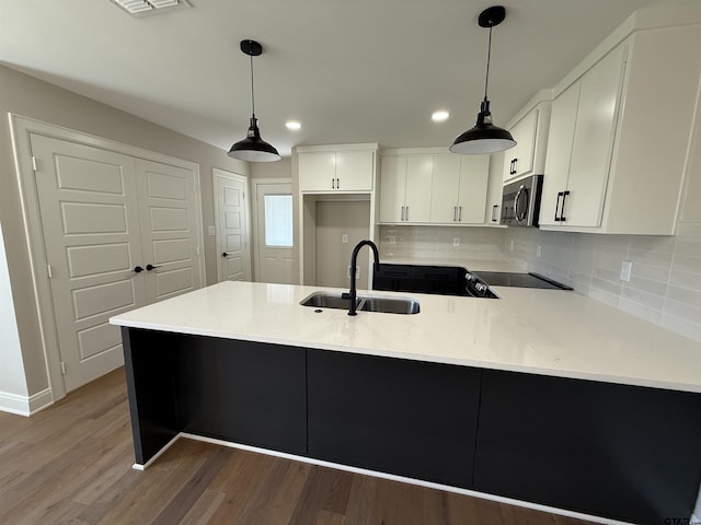 kitchen with kitchen peninsula, pendant lighting, white cabinets, and sink