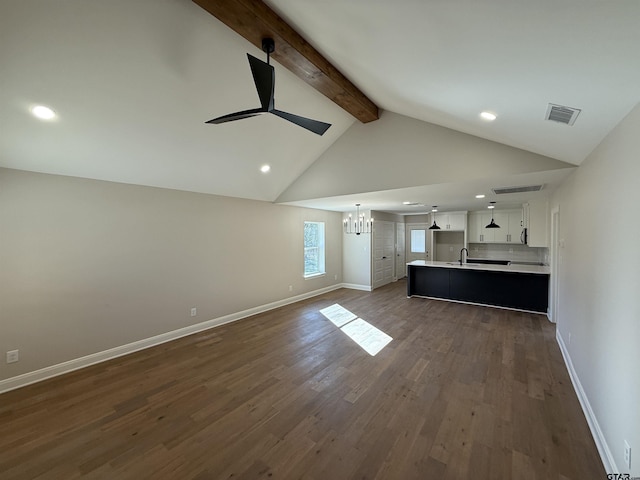 unfurnished living room with lofted ceiling with beams, sink, ceiling fan with notable chandelier, and dark wood-type flooring