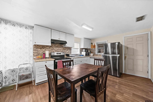 kitchen featuring stainless steel appliances, white cabinetry, light hardwood / wood-style flooring, and tasteful backsplash