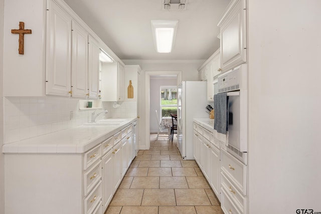 312 Savannah Dr, Tyler, TX 75703 - kitchen with white appliances, white cabinetry, light countertops, backsplash, and crown molding