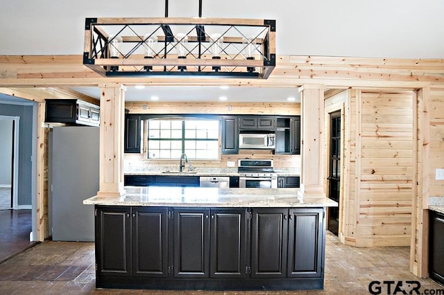 kitchen with light stone countertops, appliances with stainless steel finishes, tasteful backsplash, decorative light fixtures, and a kitchen island