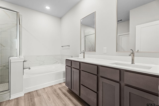 bathroom with plus walk in shower, hardwood / wood-style floors, and vanity