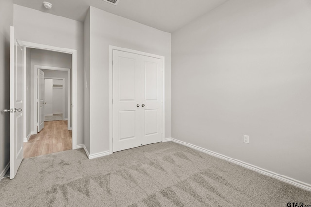 unfurnished bedroom featuring light colored carpet and a closet