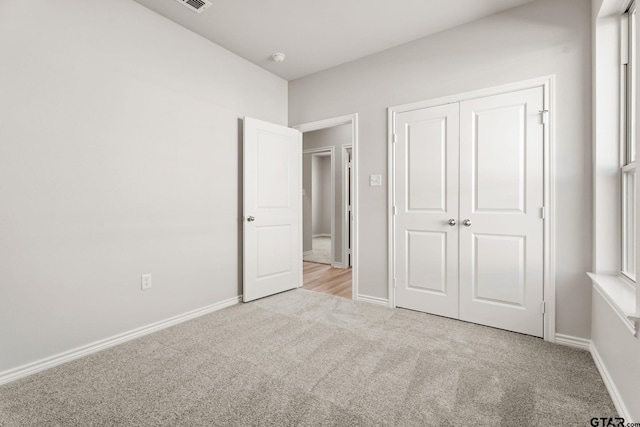 unfurnished bedroom with a closet and light colored carpet