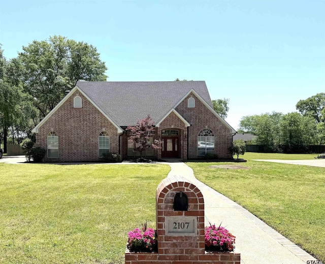 2107 Baylor Dr, Jacksonville, TX 75766 - view of front of house with brick siding, a front yard, and roof with shingles