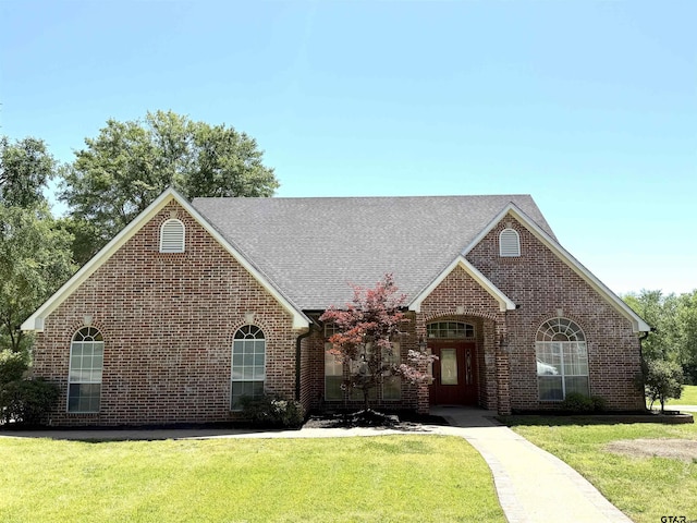2107 Baylor Dr, Jacksonville, TX 75766 - view of front facade featuring brick siding, a front yard, and a shingled roof