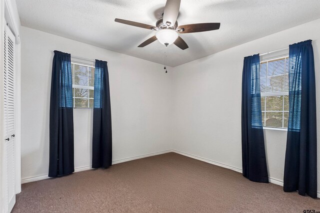 371 Shadybrook Dr, Bullard, TX 75757 - unfurnished bedroom with carpet floors, multiple windows, ceiling fan, baseboards, and a textured ceiling