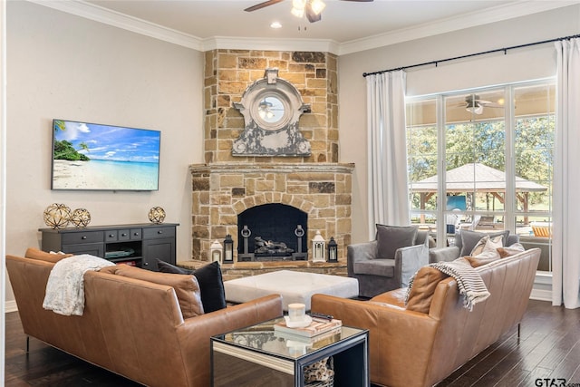 living room featuring a stone fireplace, dark wood-type flooring, ceiling fan, and crown molding