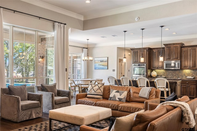 living room featuring dark wood-type flooring, an inviting chandelier, and crown molding