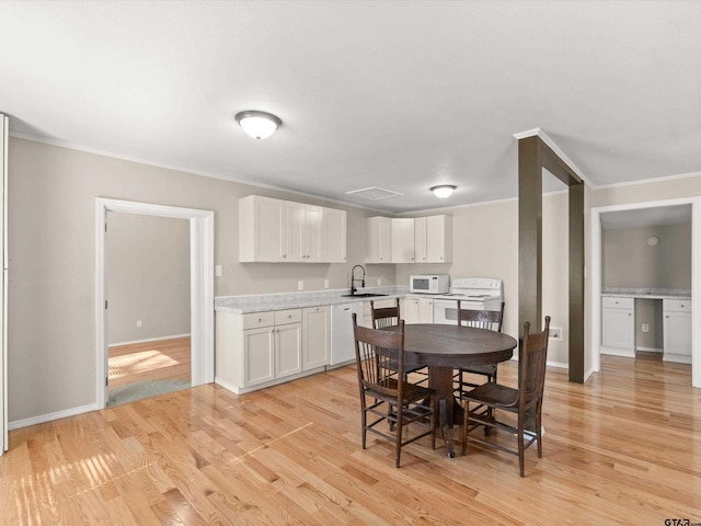 dining area with crown molding, sink, and light hardwood / wood-style flooring