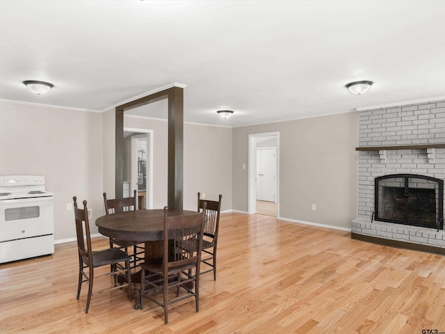 dining area with a fireplace, light hardwood / wood-style flooring, and ornamental molding