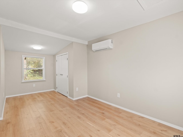 unfurnished room featuring vaulted ceiling, light hardwood / wood-style floors, and an AC wall unit