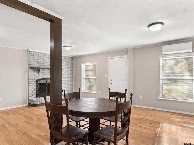 dining room with light wood-type flooring, a wall unit AC, and a healthy amount of sunlight