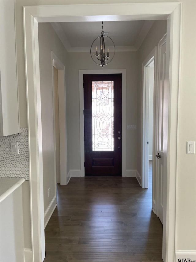 foyer with crown molding, dark wood-type flooring, and a notable chandelier