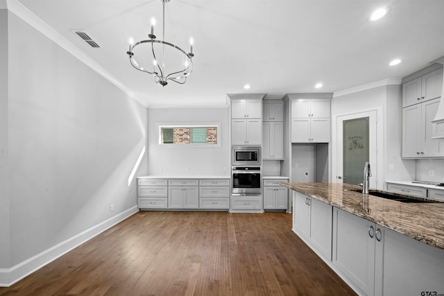 kitchen with appliances with stainless steel finishes, stone countertops, pendant lighting, sink, and backsplash