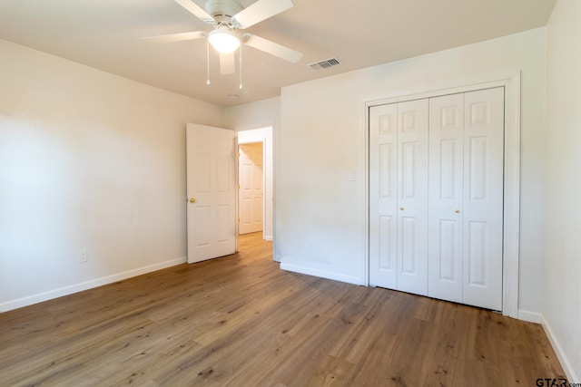 unfurnished bedroom featuring ceiling fan, a closet, and hardwood / wood-style flooring