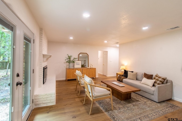 living room with a brick fireplace and light wood-type flooring