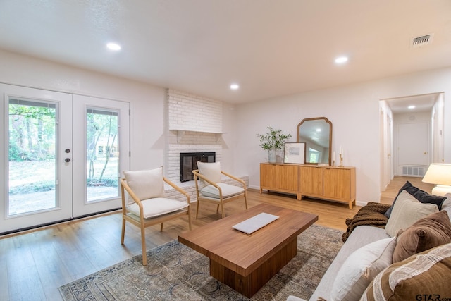 living room featuring a fireplace, french doors, and light wood-type flooring