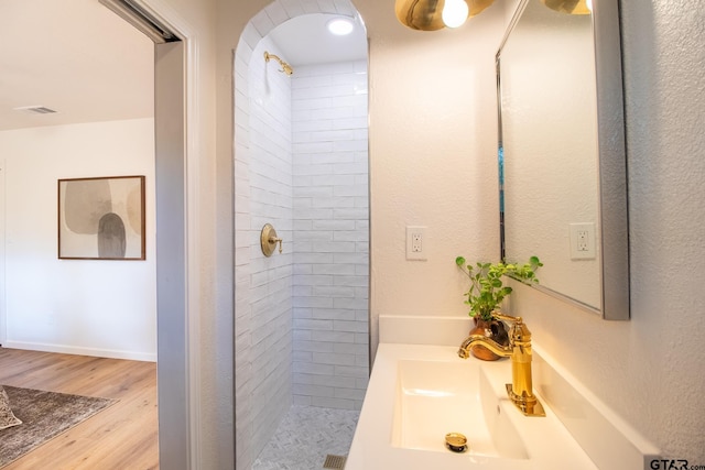 bathroom with vanity, a tile shower, and wood-type flooring