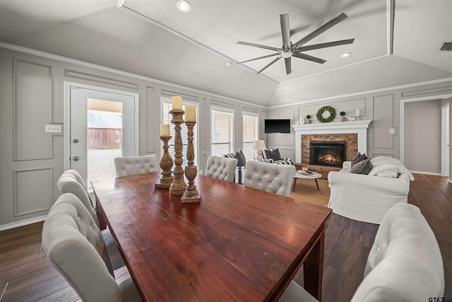 dining space featuring dark wood finished floors, a decorative wall, ceiling fan, and vaulted ceiling