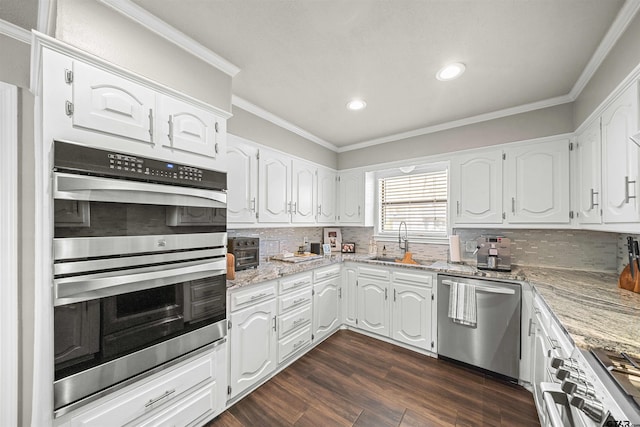 kitchen with dark wood-style flooring, a sink, appliances with stainless steel finishes, crown molding, and backsplash