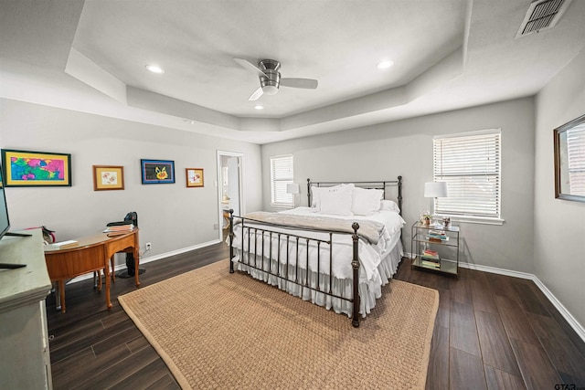 bedroom featuring visible vents, a raised ceiling, baseboards, and dark wood-style flooring