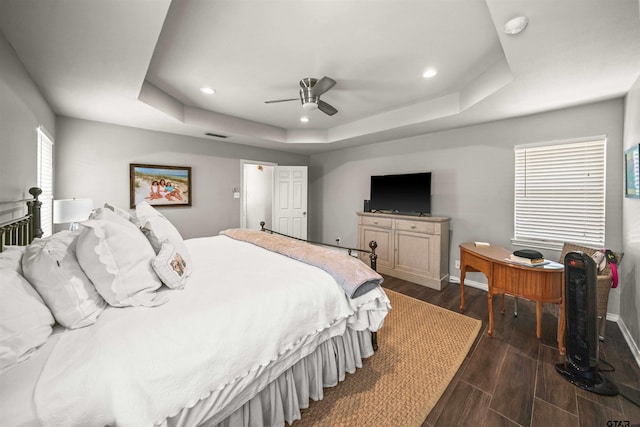 bedroom featuring dark wood-style floors, recessed lighting, baseboards, and a tray ceiling