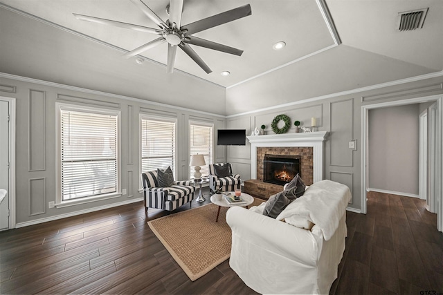 living room with visible vents, dark wood finished floors, a decorative wall, a brick fireplace, and vaulted ceiling