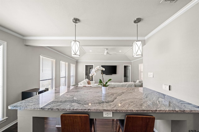 kitchen with light stone counters, a breakfast bar, ornamental molding, and vaulted ceiling