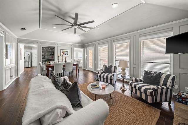 living area with dark wood-style floors, a decorative wall, visible vents, and vaulted ceiling