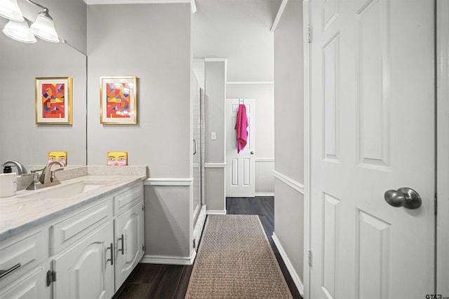 bathroom with a stall shower, baseboards, wood finished floors, and vanity