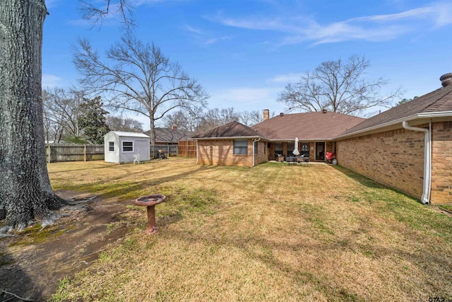 view of yard with an outdoor structure, a storage unit, a fenced backyard, and a patio