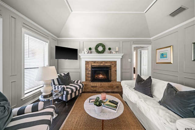 living area featuring visible vents, vaulted ceiling, a fireplace, wood finished floors, and a decorative wall