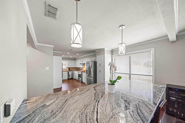 dining room with a textured ceiling, dark wood-type flooring, visible vents, and ornamental molding