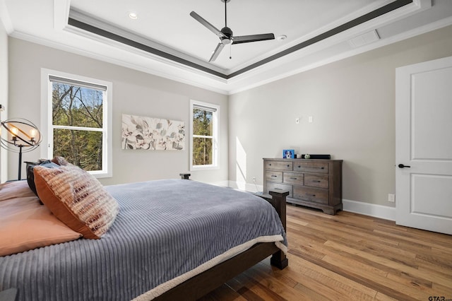 bedroom with crown molding, ceiling fan, a raised ceiling, and light hardwood / wood-style floors