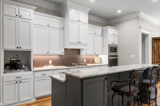 kitchen featuring light stone countertops, stainless steel appliances, white cabinets, and a kitchen island